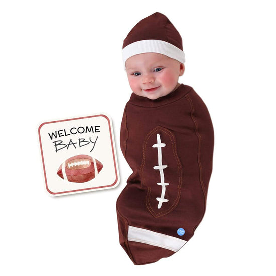 Newborn baby wrapped in brown football-themed baby cocoon swaddle with matching hat and welcome announcement card